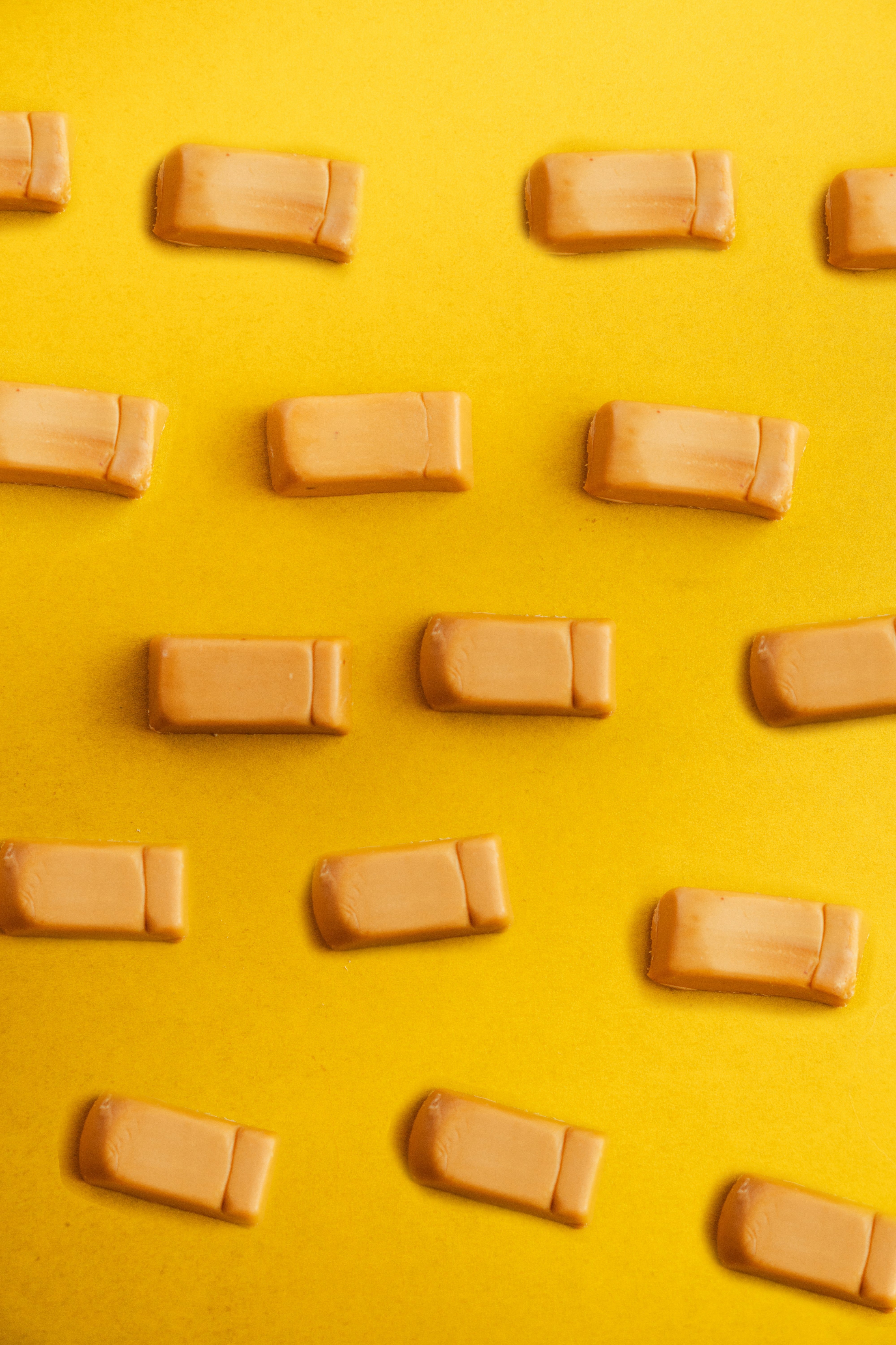 Doce de leite Uai Vida — pattern grid de tablets cubo coral espalhados sobre fundo amarelo pop